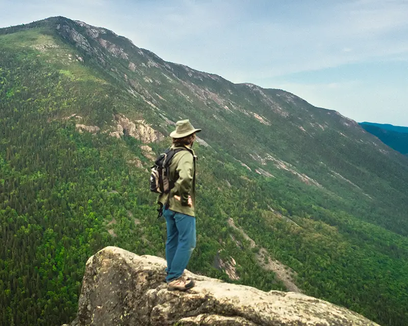 A man standing upon a rock surveying a mountain range