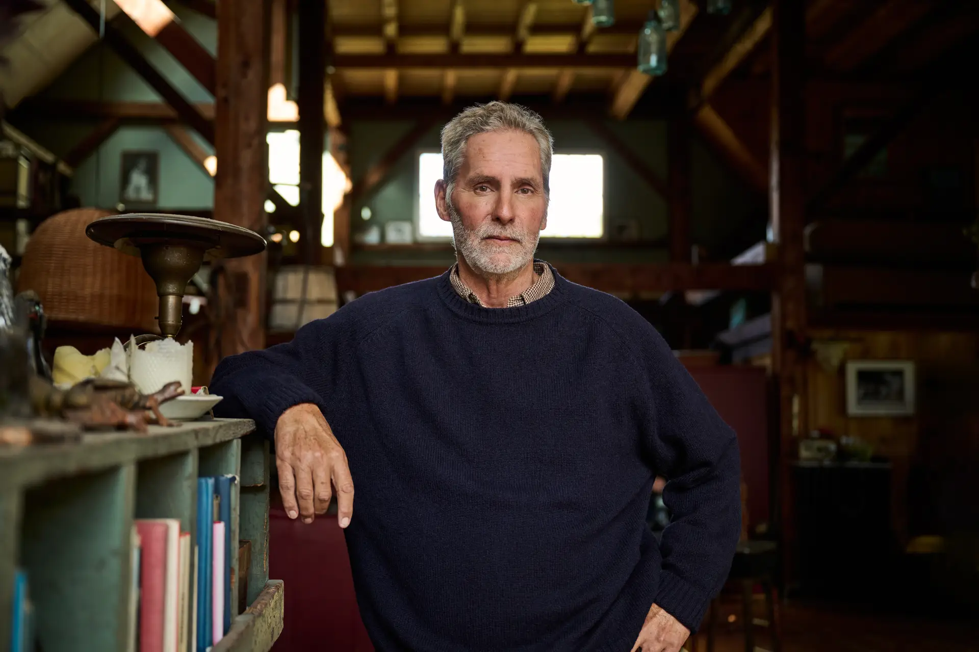 Man standing in hallway, leaning on a bookcase