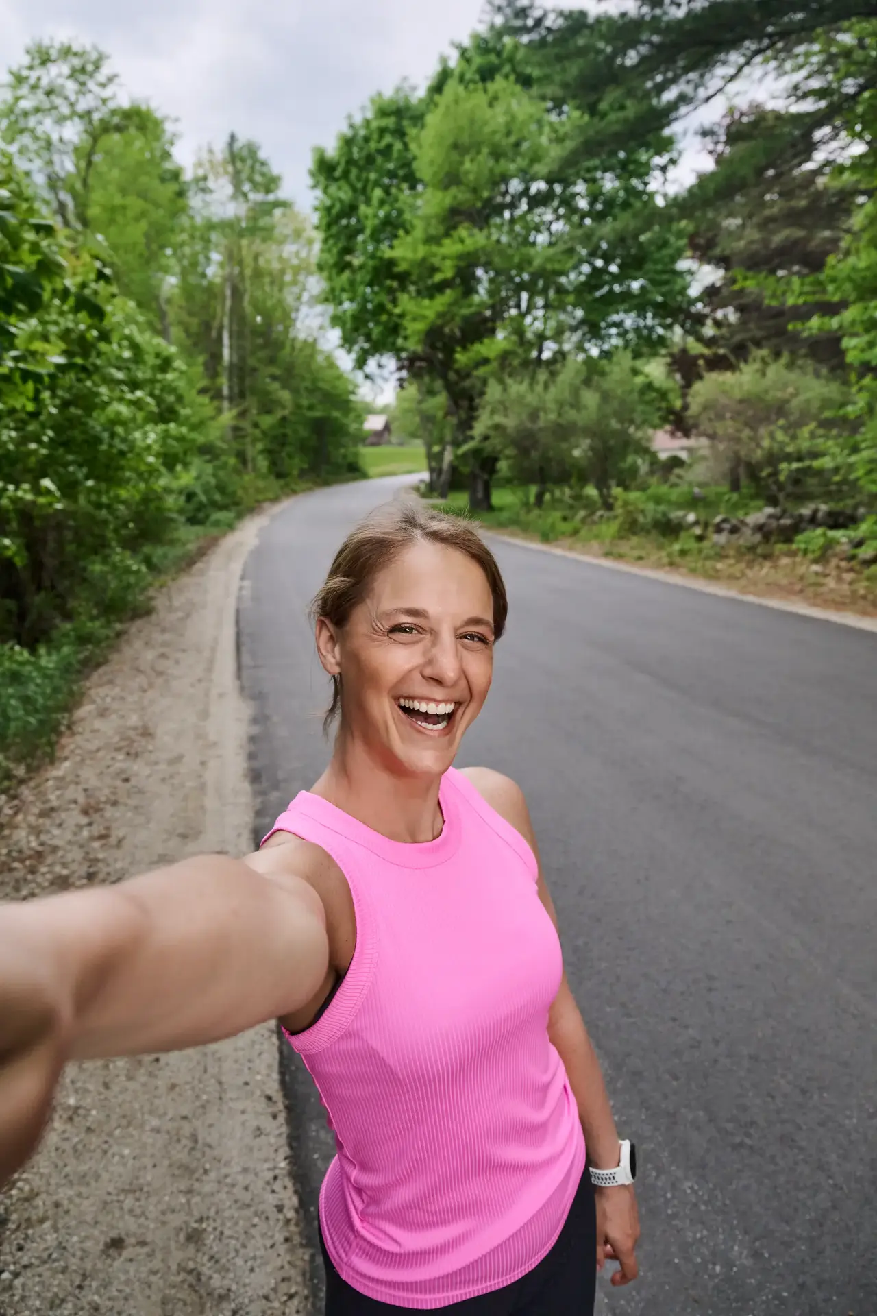 Woman in a pink shirt taking a selfie on a rural road