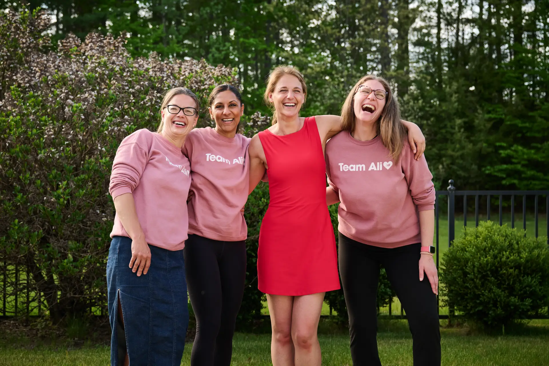 Four women standing arm in arm together outdoors