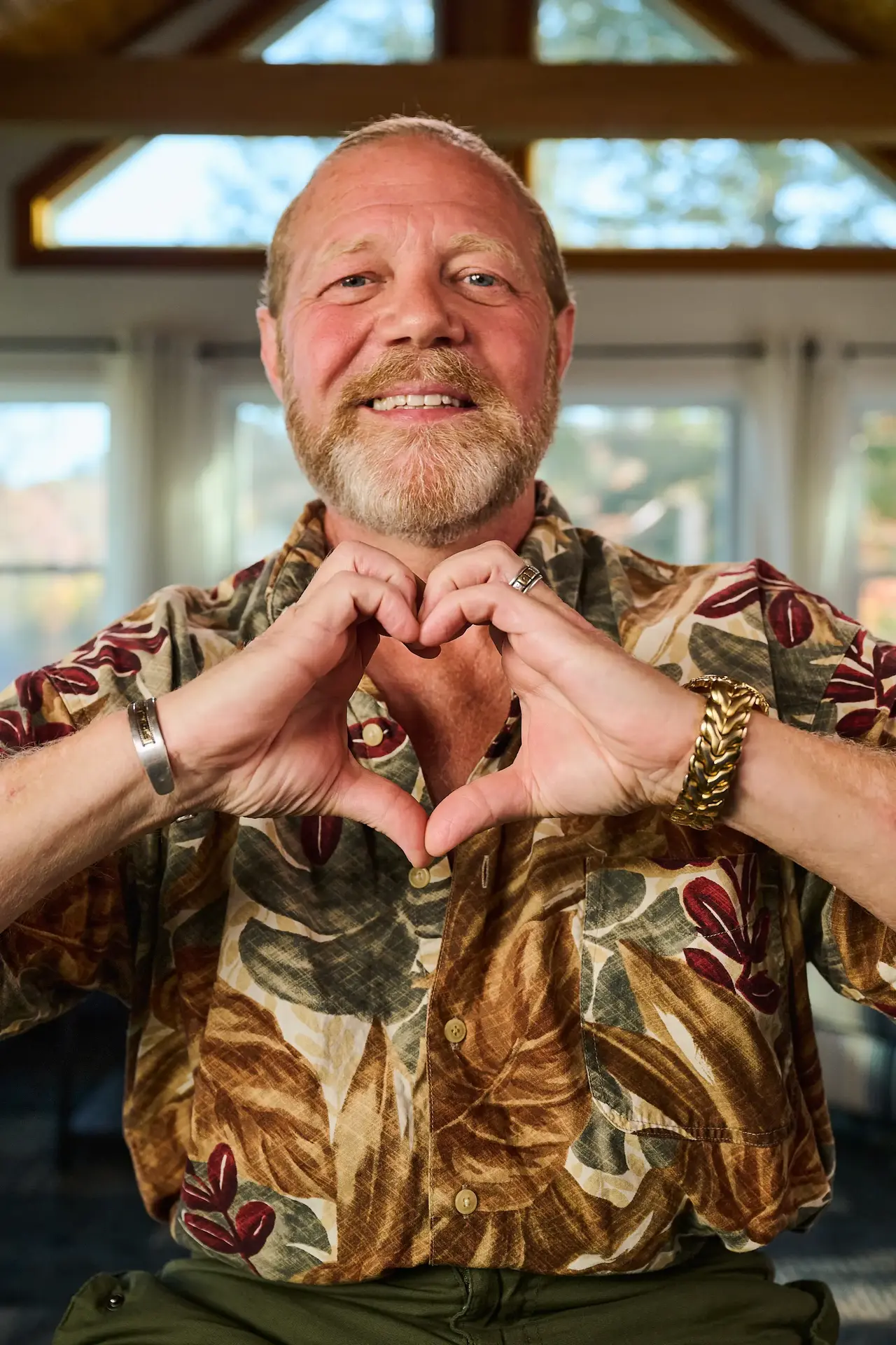 A smiling man making the sign of a heart using his hands
