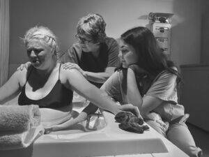 Woman giving birth supported by two caregivers