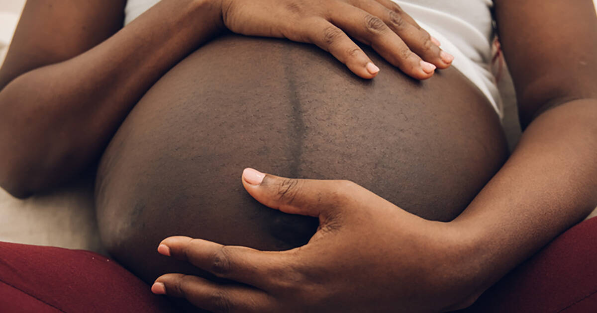 Hands holding the belly of a pregnant woman