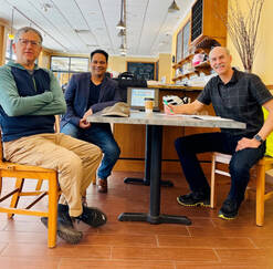 Three men sit around a table