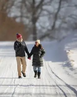 Two people walk along a snow-covered road