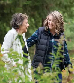 A young woman helps an older woman walking outdoors