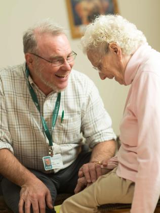 A seated provider laughing with a seated geriatric patient