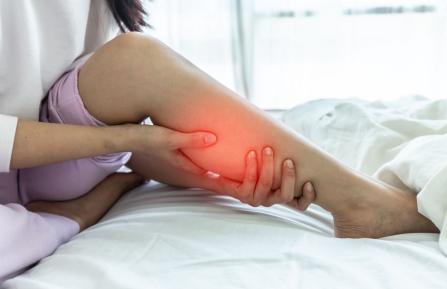A person holding the calf of their leg, which is glowing red to indicate pain