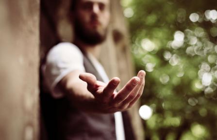 A man extending an open hand, palm up, towards the viewer