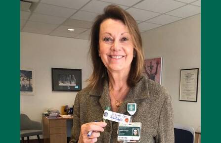 Photo of Joanne Conroy, MD, on a green background, holding a handwritten note.