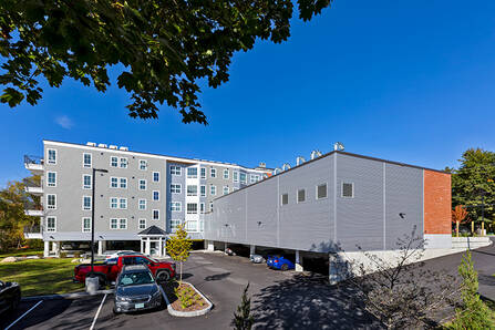 Exterior view of 195 Mechanic Street apartments, parking garage, and parking lot on a sunny summer day