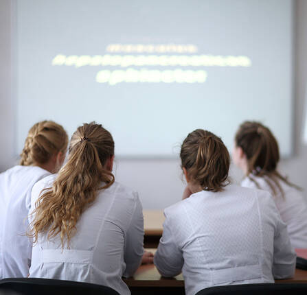 four health care providers shown from the back looking at blurred out words on a whiteboard