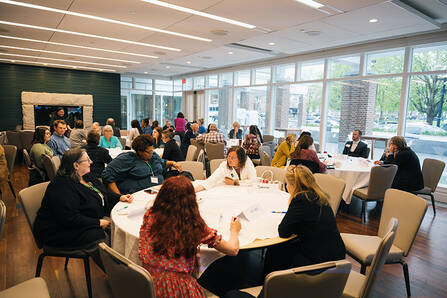 Symposium participants sitting at round tables in a conference room