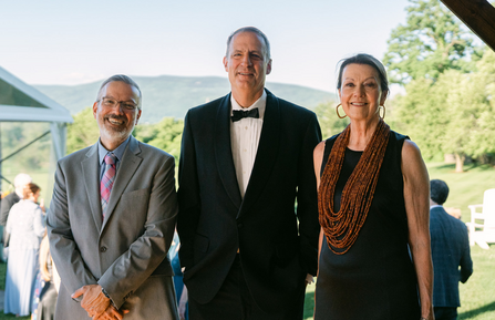 A photo of three people standing in front of a scenic background