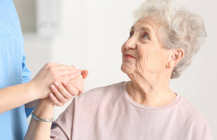 Older women holding hands with care taker.