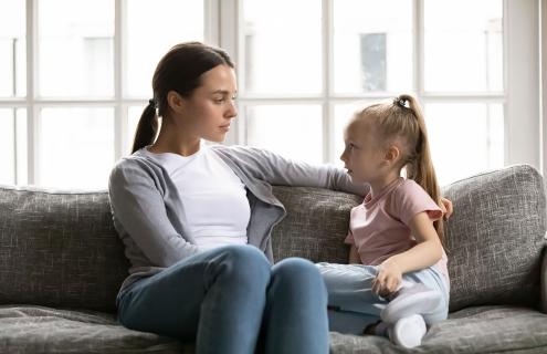 A parent and a young child sitting together on a sofa