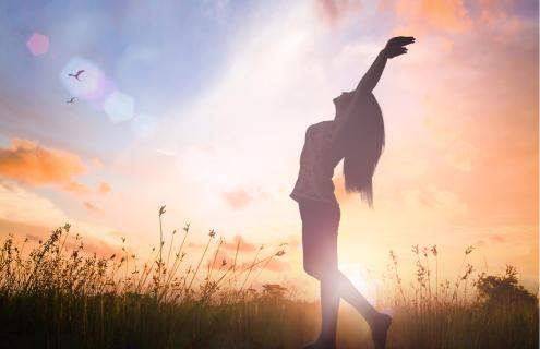 Woman stretching in a field at sunrise