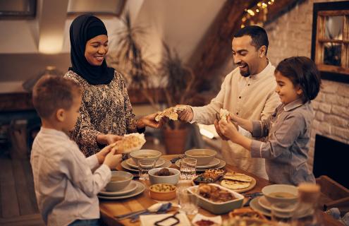 Muslim family sharing pita bread while eating dinner on Ramadan