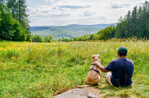 man sitting in field with a dog