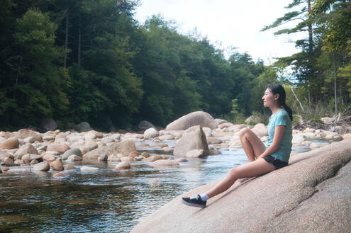 woman relaxing by a calm brook