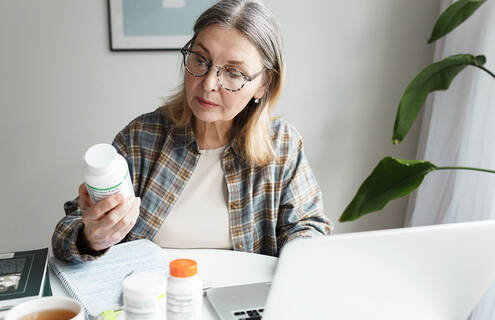 Woman examining bottle of medication at home.