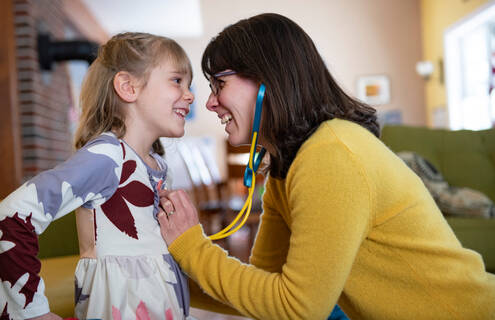 Mother, right, plays with her young daughter, left, using a toy stethoscope