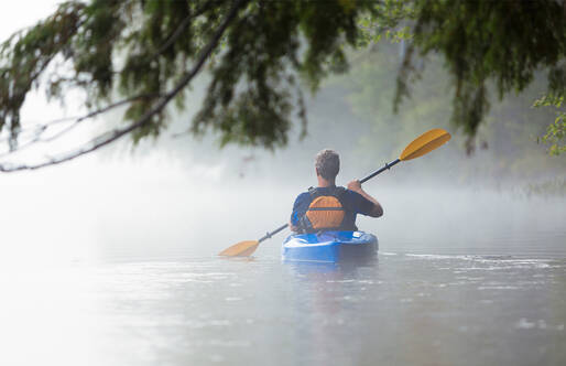 man kayaking in pond 