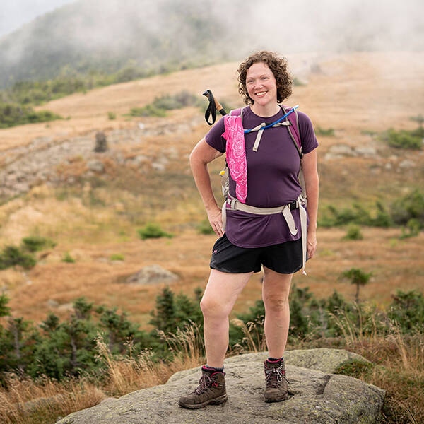 A woman stands on rock on a hiking trail