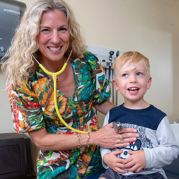 A provider and a child smile at the camera