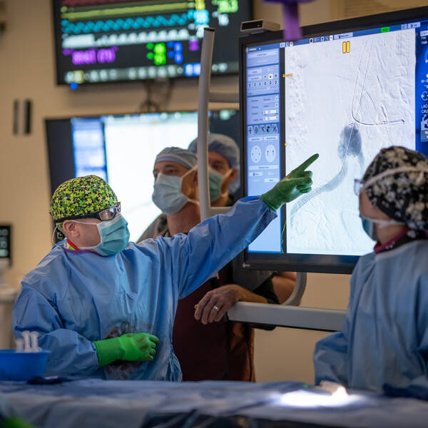 Cardiac surgeon points to screen while other providers watch