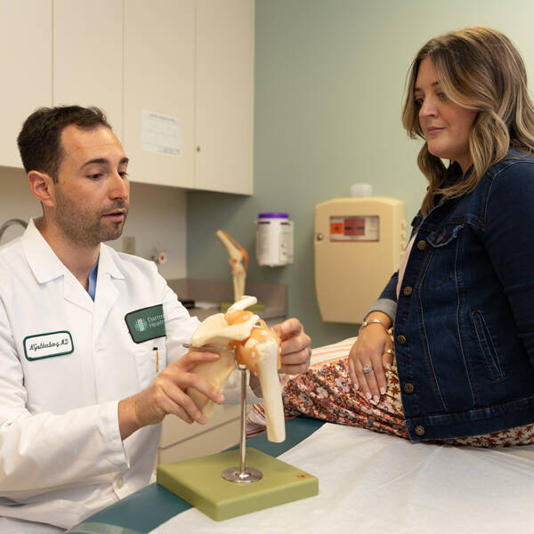 Orthopaedics provider demonstrates procedure on a model while patient watches