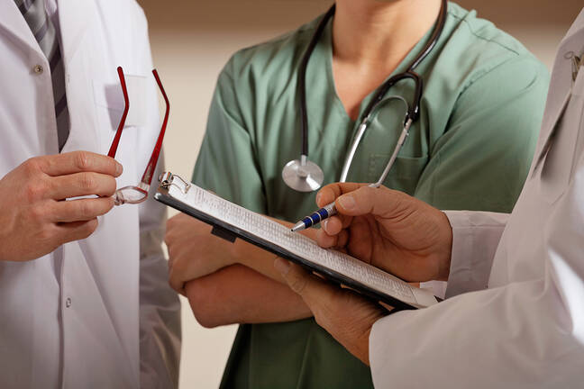 three health care providers shown from the neck down to the torso