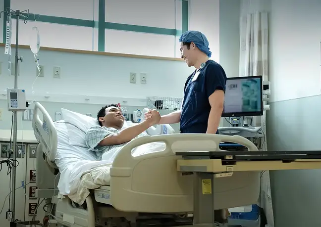 Provider shakes hand with patient in a hospital bed