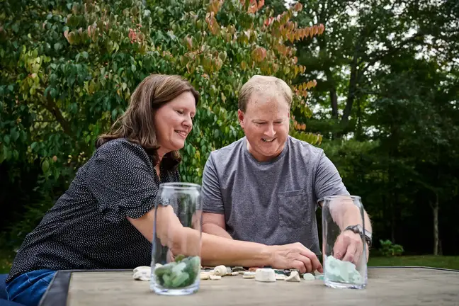 Lisa and Jeff Clark sit at an outdoor table, examining pieces of sea glass