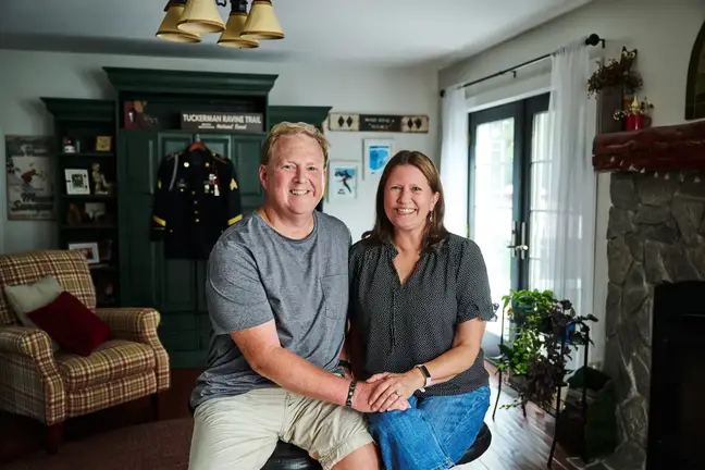 Jeff and Lisa Clark, holding hands and seated in their living room