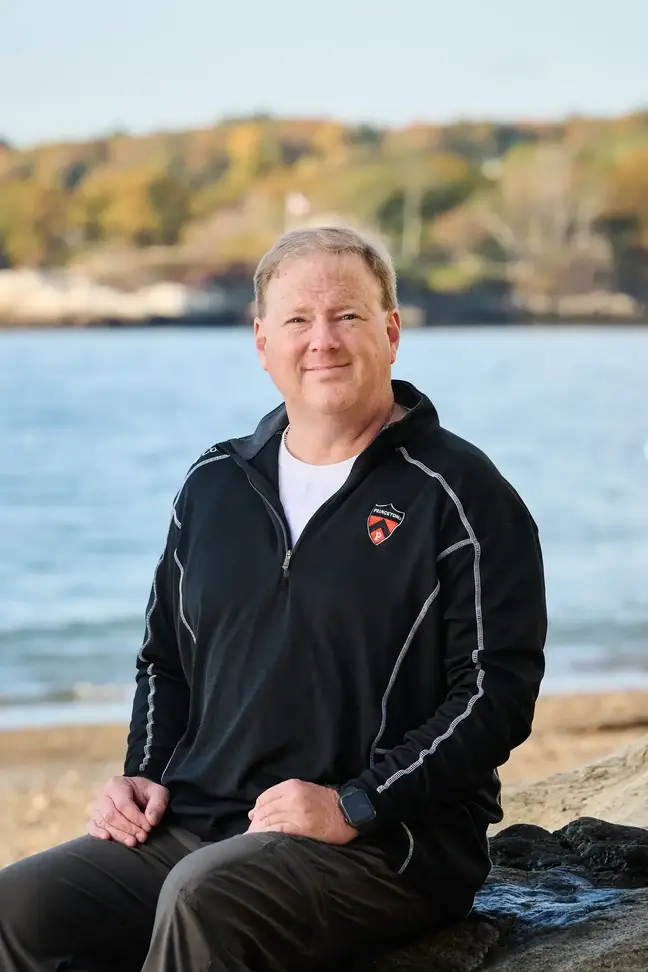 Jeff Clark seated on a rock by the ocean