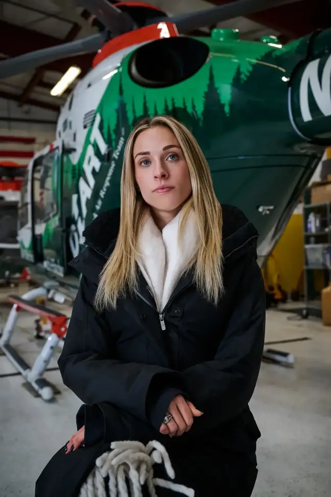 A woman seated behind a DHART helicopter in its hangar