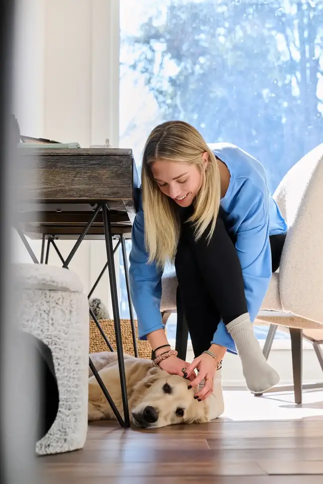A woman reaches down from her desk to pet her dog