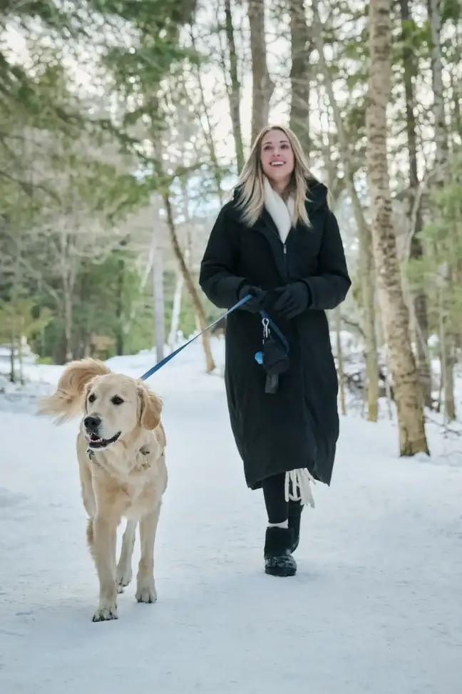 A woman walks her dog in a snowy landscape