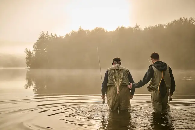 Joe Monninger helps a friend fly fish in a lake
