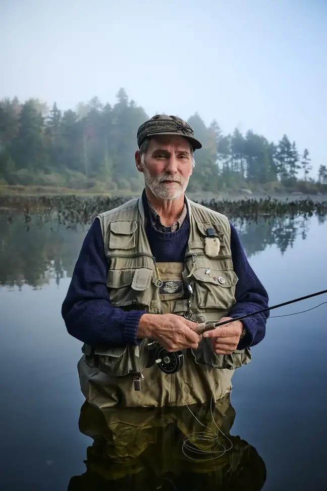 Fly fisherman wading in lake facing camera