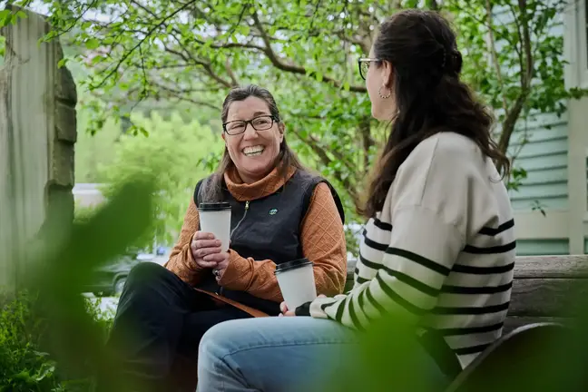 Two women sit and talk outdoors