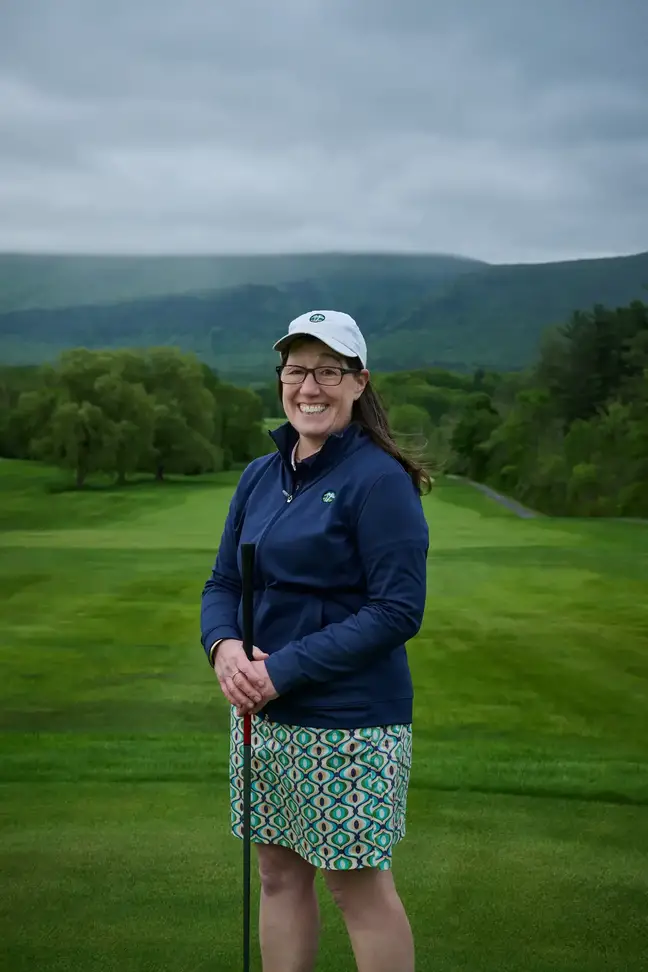 Smiling woman leaning on a golf club at a golf club
