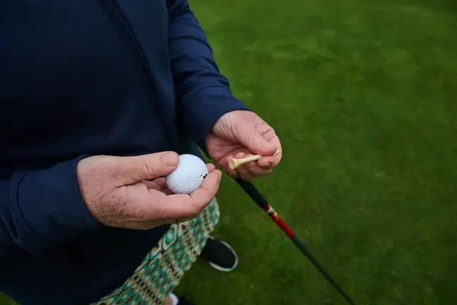 Hands holding a golf ball and tee