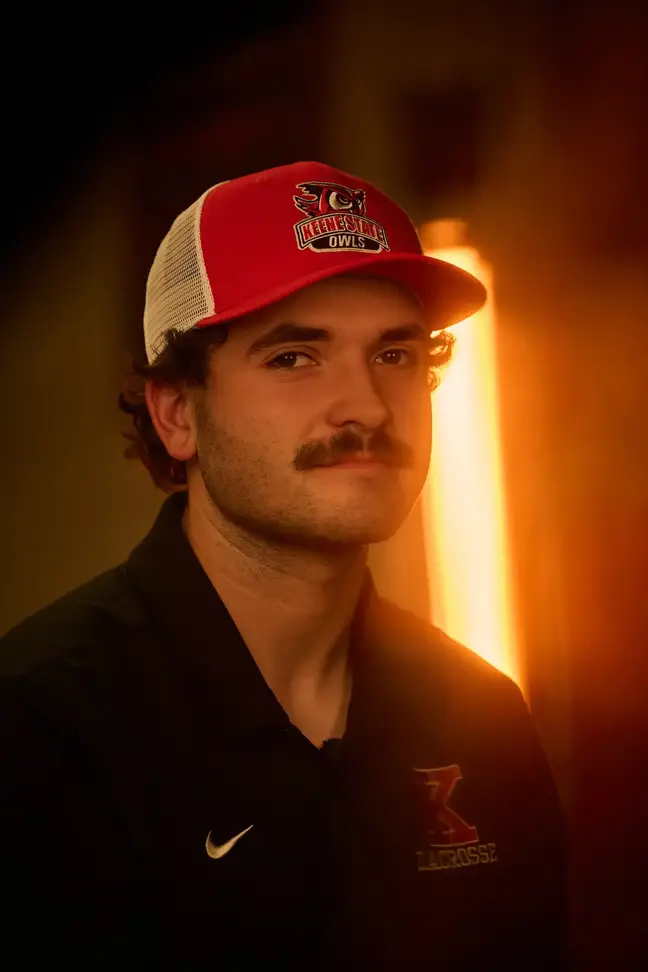 Head shot of a young man with mustache wearing a trucker's cap