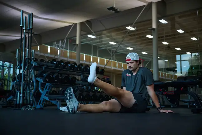 Man stretches leg on gym floor