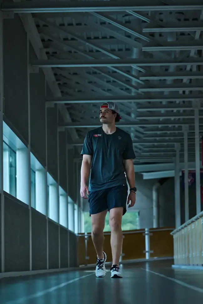 A man in gym clothes walks down a hallway