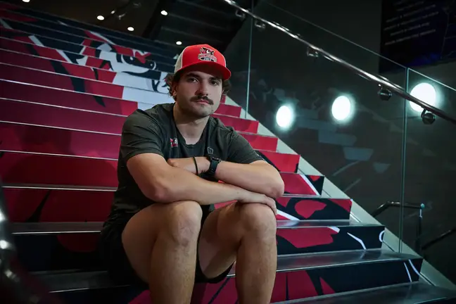 Man in gym clothes sits on bleachers