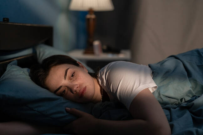 A woman lies awake in bed with her eyes open