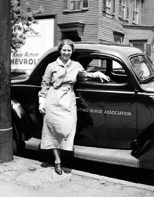 historical photo of nurse standing next to automobile with Visiting Nurse Association logo on door 